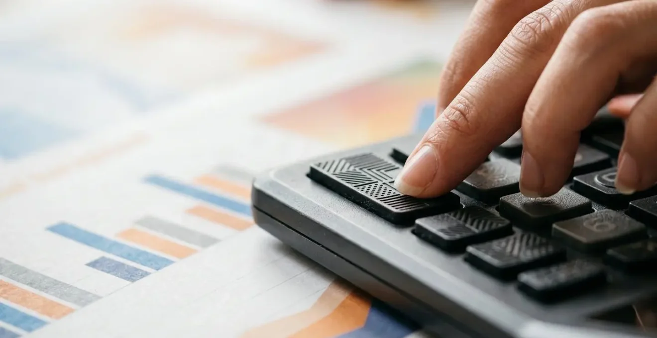 Gros plan sur des mains utilisant une calculatrice pour évaluer les économies d'un prêt immobilier